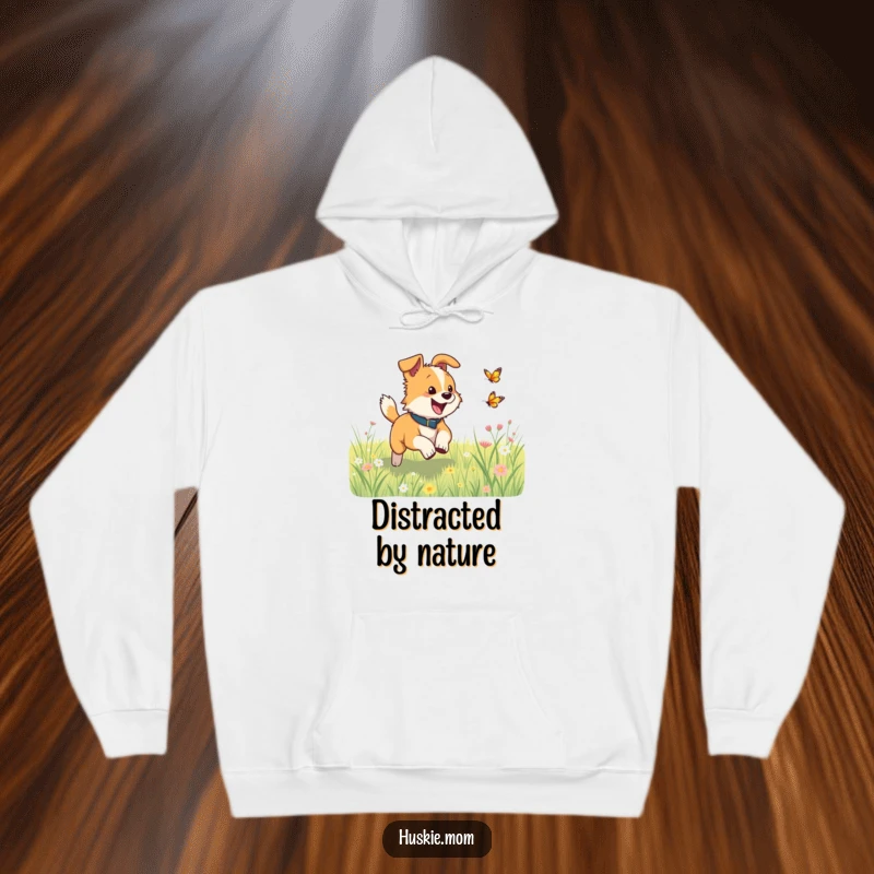 Funny dog excitedly chasing a fluttering butterfly in a meadow on a cozy hoodie, perfect for adventurers.