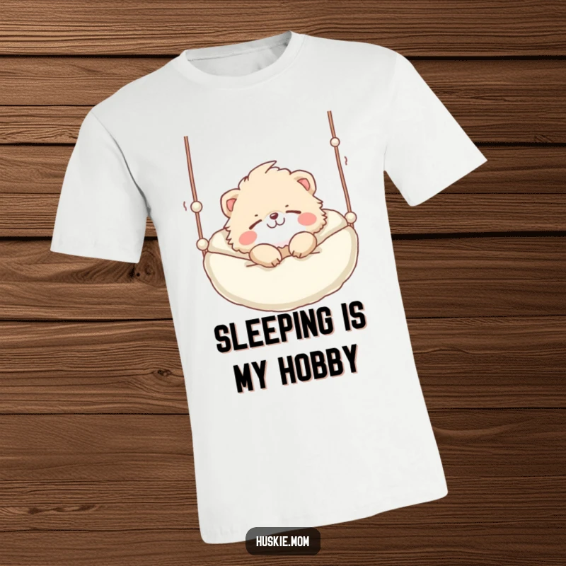 Funny T-Shirt: A fluffy animal with a playful grin soundly sleeping in a suspended bed, the picture of peaceful rest.